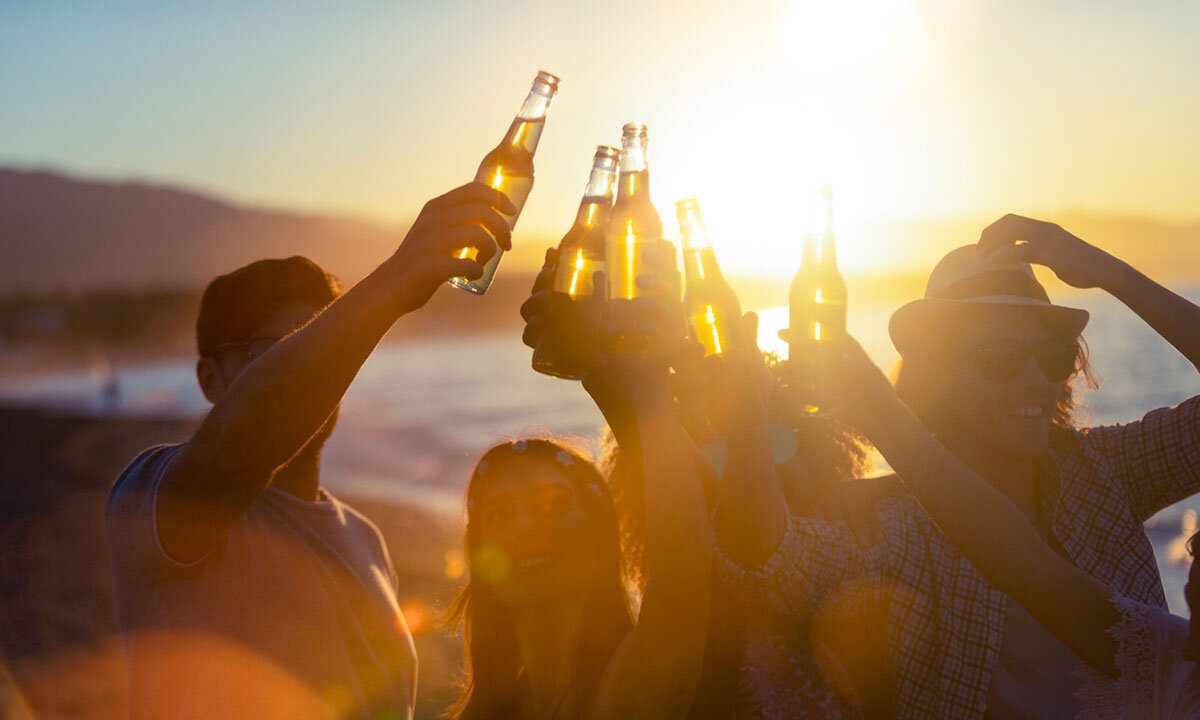 Friends raise beer bottles in a toast at an outdoor party