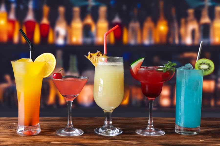 Five cocktails with garnishes on bar counter